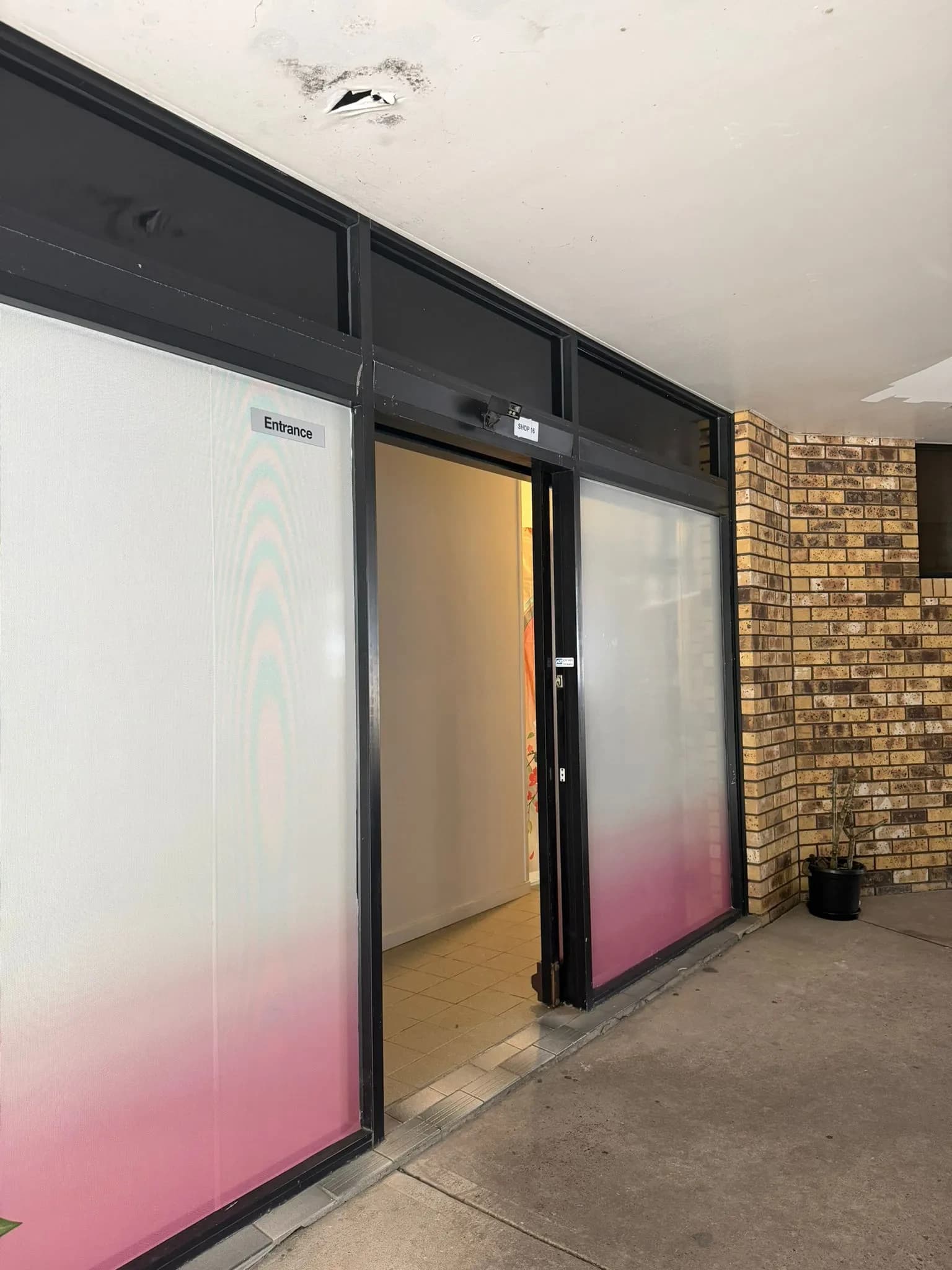 The private entrance with frosted pink-gradient glass and entrance sign
