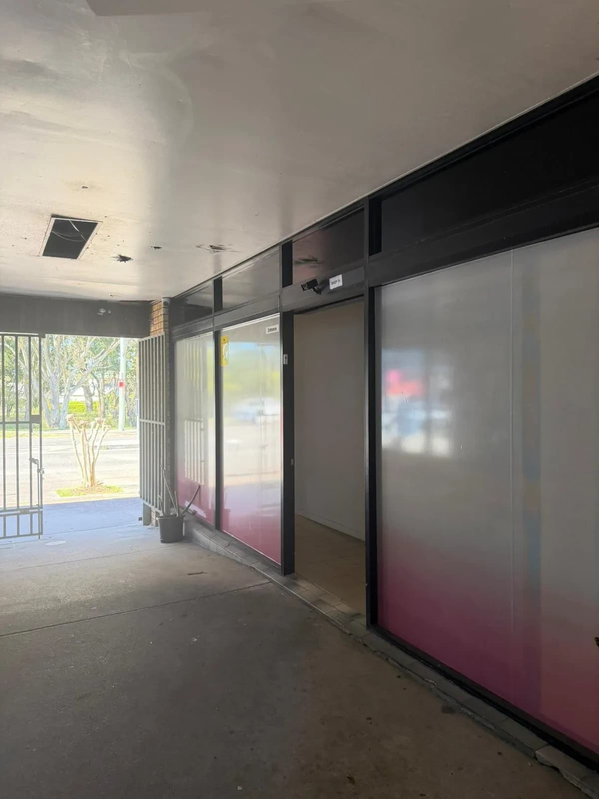 Quiet covered arcade walkway with pink-gradient frosted glass leading to Blackall Remedial Massage